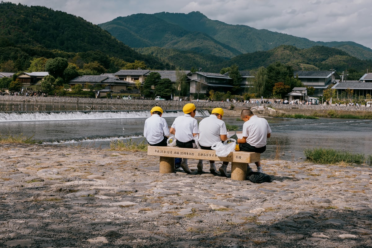 Crianças de escola almoçando na beira do rio em Kyoto